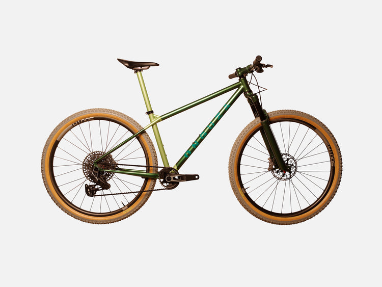 A side-on view of the ONGUZA Rooster hard tail mountain bike in a size large, in the Boomslang Green color. The bike features a suspension fork, also painting in the dark green color. The seat tube and seat post are a pearled Sage color with the front and rear triangles in a metallic dark forrest green color. The ONGUZA wordmark on the down tube is in a Teal blue-green. The carbon wheels on the bike are made by South Industries in South Africa and feature grey-tread tyres with tan side-walls.